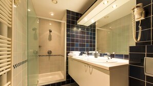 Ein modernes Badezimmer mit einer Duschkabine, einem Waschtisch mit zwei Becken und einem großen Spiegel.