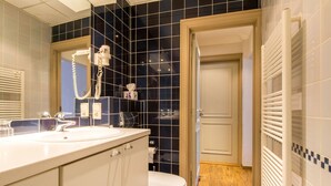 Un baño con lavamanos blanco, un espejo, inodoro y zona de ducha.