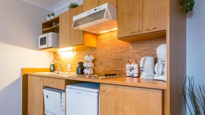 Una cocina compacta con armarios de madera, microondas, cafetera y lavavajillas pequeño.