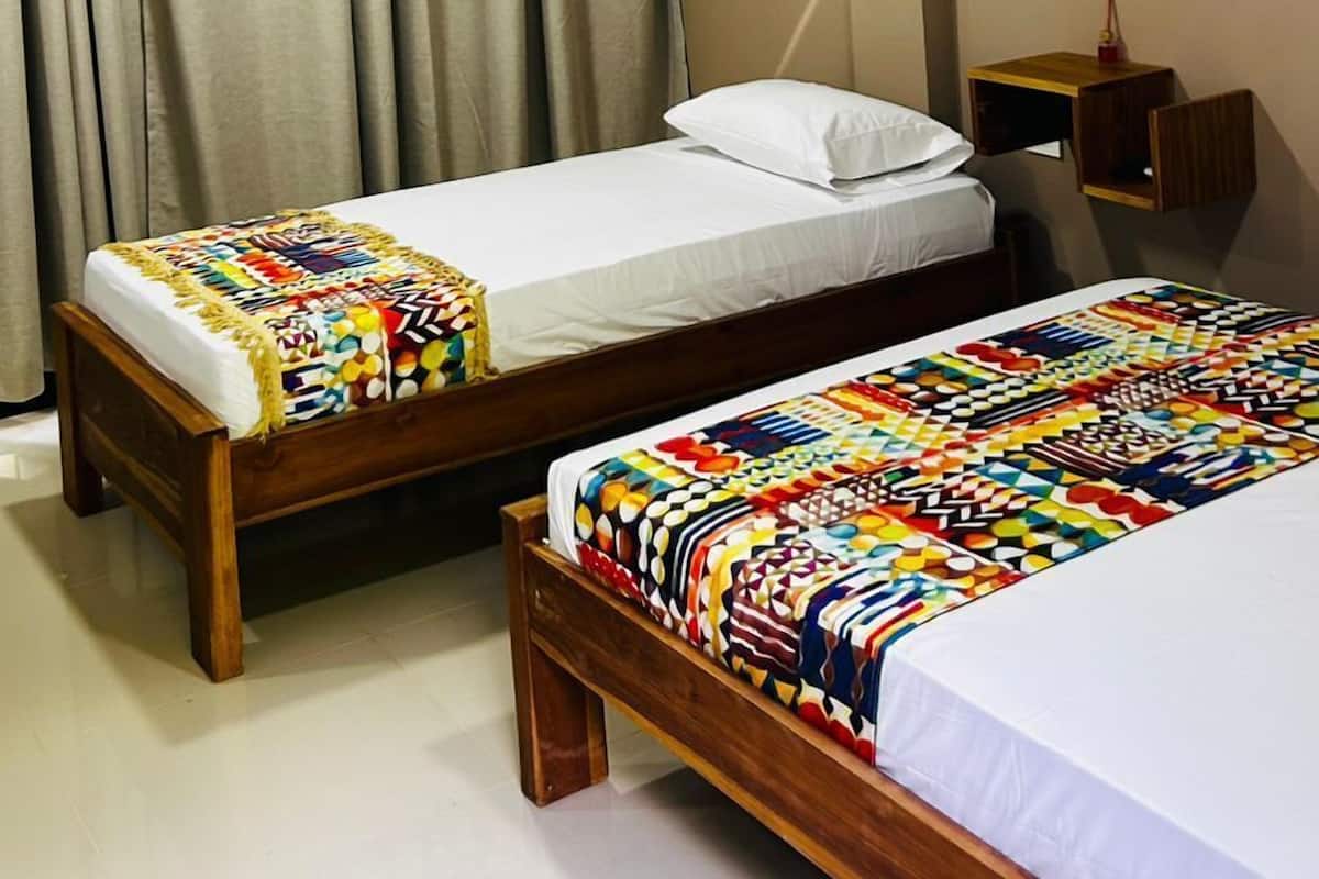 A hotel room with two beds, a wooden headboard, a mirror, and a wall-mounted light fixture.