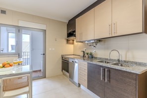 A modern kitchen with a dishwasher, double sink, and a dining area with a table and chairs. - #368 T2 Apartment | Sea View & Terrace Albufeira (Albufeira)