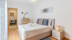 Een slaapkamer met een bed, nachtkastje en een klein kastje.