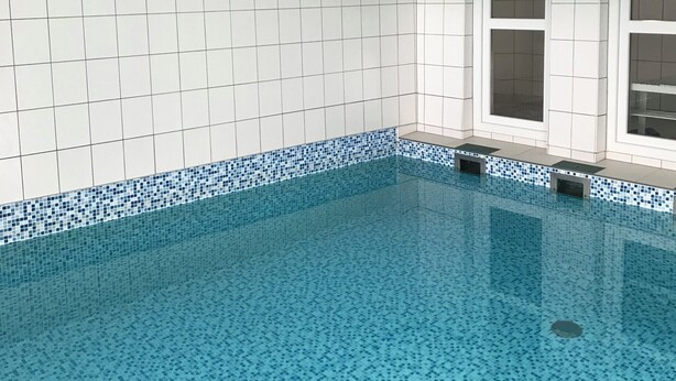 En swimmingpool med blå mosaikplattor, vita väggar och en skylt som visar att strumpor inte är tillåtna.