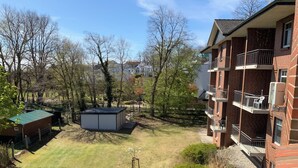 Ett bostadsområde med en flervåningsbyggnad i tegel, ett litet förråd och en gräsyta med träd.