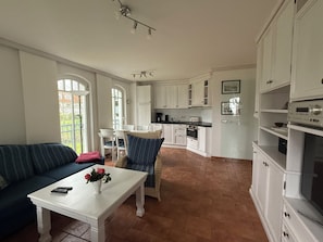 A spacious living area with a sofa, a coffee table with a vase of flowers, and a dining area with chairs and a table. - ***STRANDPALAIS*** Apartment "Steuerbord" only 150 m from the beach (Kühlungsborn)