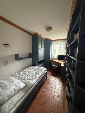 A bedroom with a bed, a desk, and a bookshelf. - ***STRANDPALAIS*** Apartment "Steuerbord" only 150 m from the beach (Kühlungsborn)
