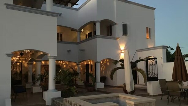 Un edificio de varios niveles con piscina, mobiliario exterior y un patio cubierto.