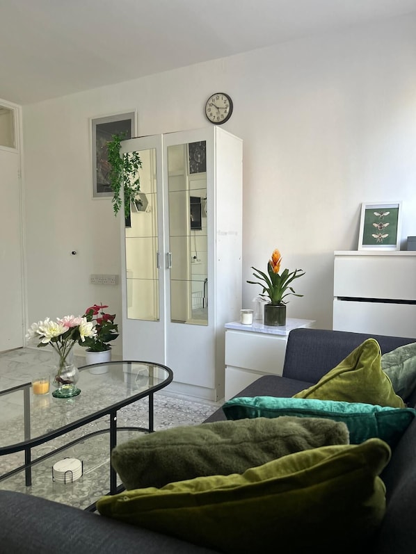 A living room with a sofa, a coffee table, a cabinet, a clock, and a plant.