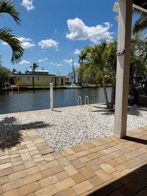 A waterfront property with a dock, a small boat, and a building with a blue roof. - The Island Shanty (Matlacha)