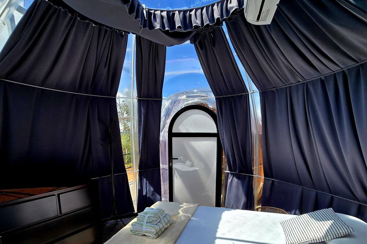 A tent-like room with a bed, a table, and a window.