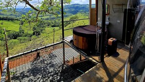 A modern outdoor bathroom with a hot tub, a wooden stool, and a view of a lush green landscape. - Dulces Momentos PZ (San Pedro)