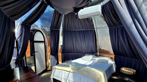 A tented room with a bed, a small table, and a wardrobe. - Dulces Momentos PZ (San Pedro)