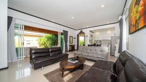 A modern living room with leather sofas, a coffee table, and a view of a kitchen and outdoor area. - Tropical Pool Villa with 3 Bedrooms in Rawai (Tambon Rawai)