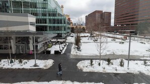 Un edificio moderno con entrada de garaje, un espacio exterior cubierto y suelo cubierto de nieve.