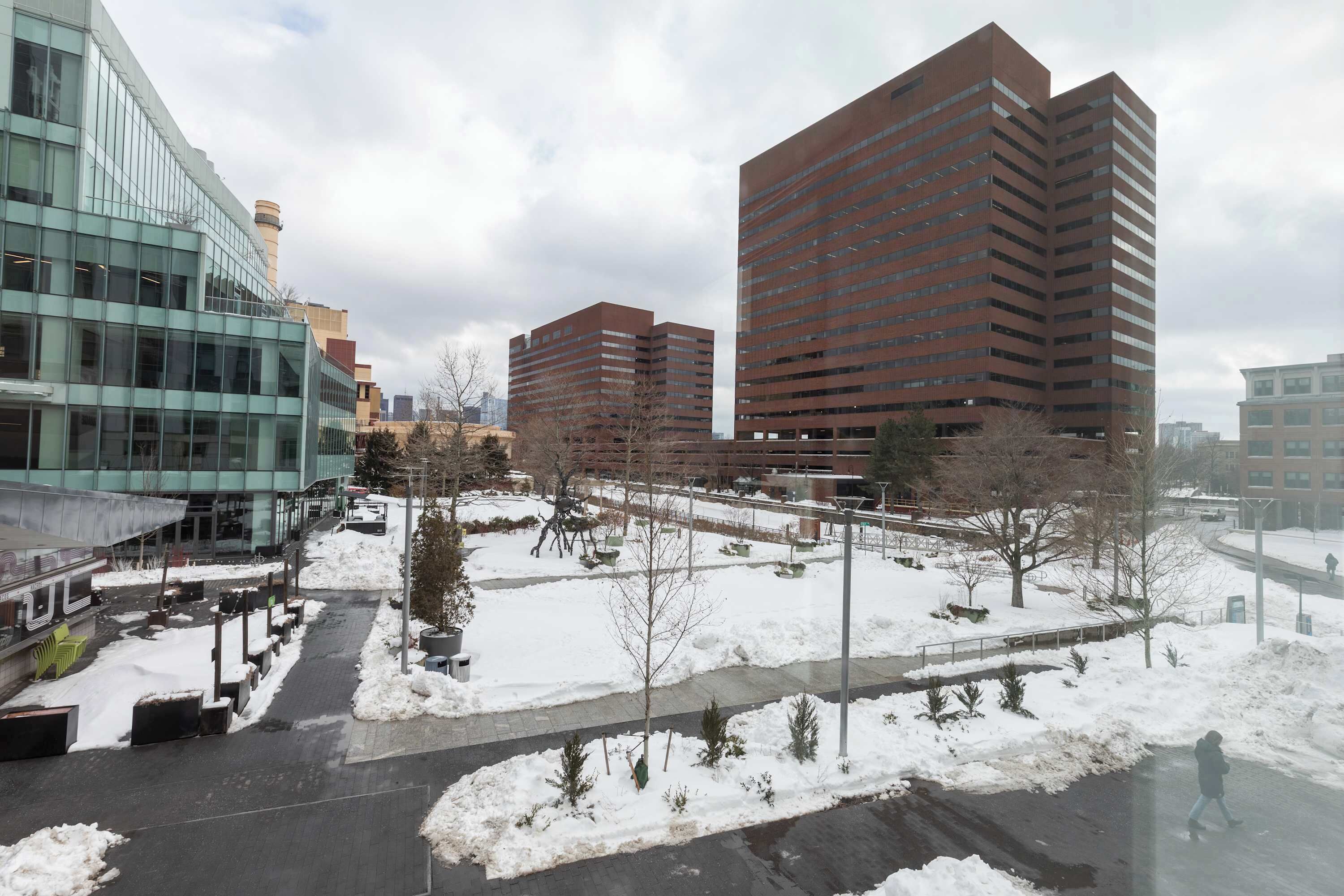 A modern urban area with buildings, a snow-covered plaza, and a pedestrian pathway.