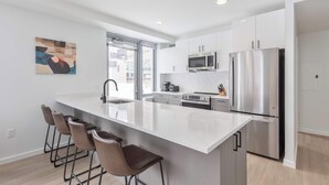 Una cocina moderna con una isla grande, electrodomésticos de acero inoxidable y taburetes de bar.