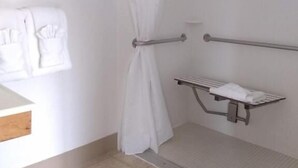 A bathroom with a shower, a towel rack, and a shelf with a towel. - The Orca Inn (Friday Harbor)