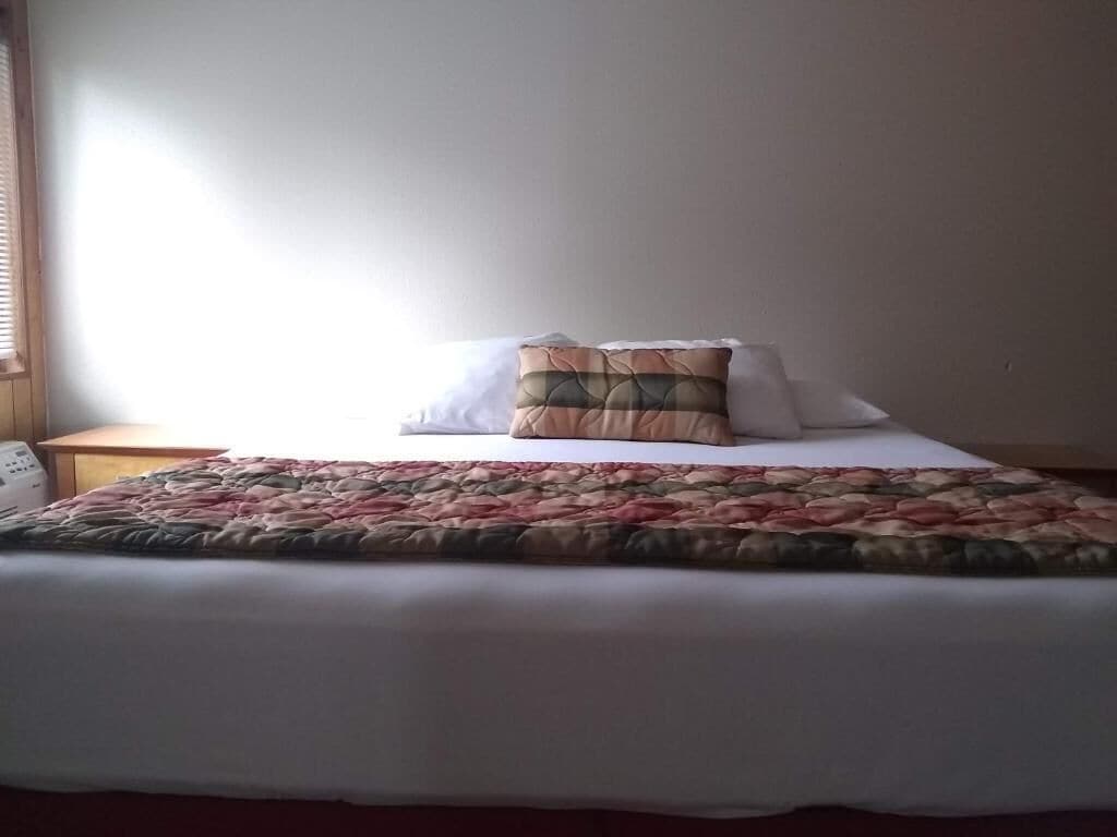 Un lit avec une couvre-lit à motifs floraux, un oreiller et une table de chevet avec une lampe.