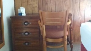 A wooden chair and a wooden dresser in a room with a wooden panel wall. - The Orca Inn (Friday Harbor)