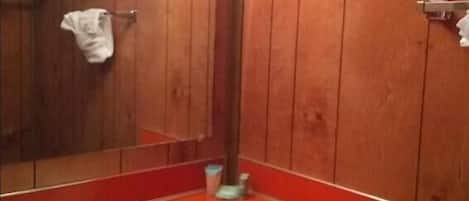 A bathroom with wooden walls, a white sink, and a mirror.