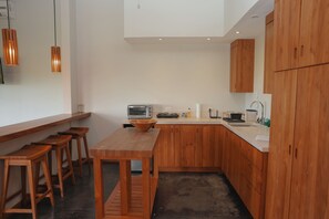Una cucina moderna con mobili in legno, forno integrato, lavello e zona pranzo con sgabelli.