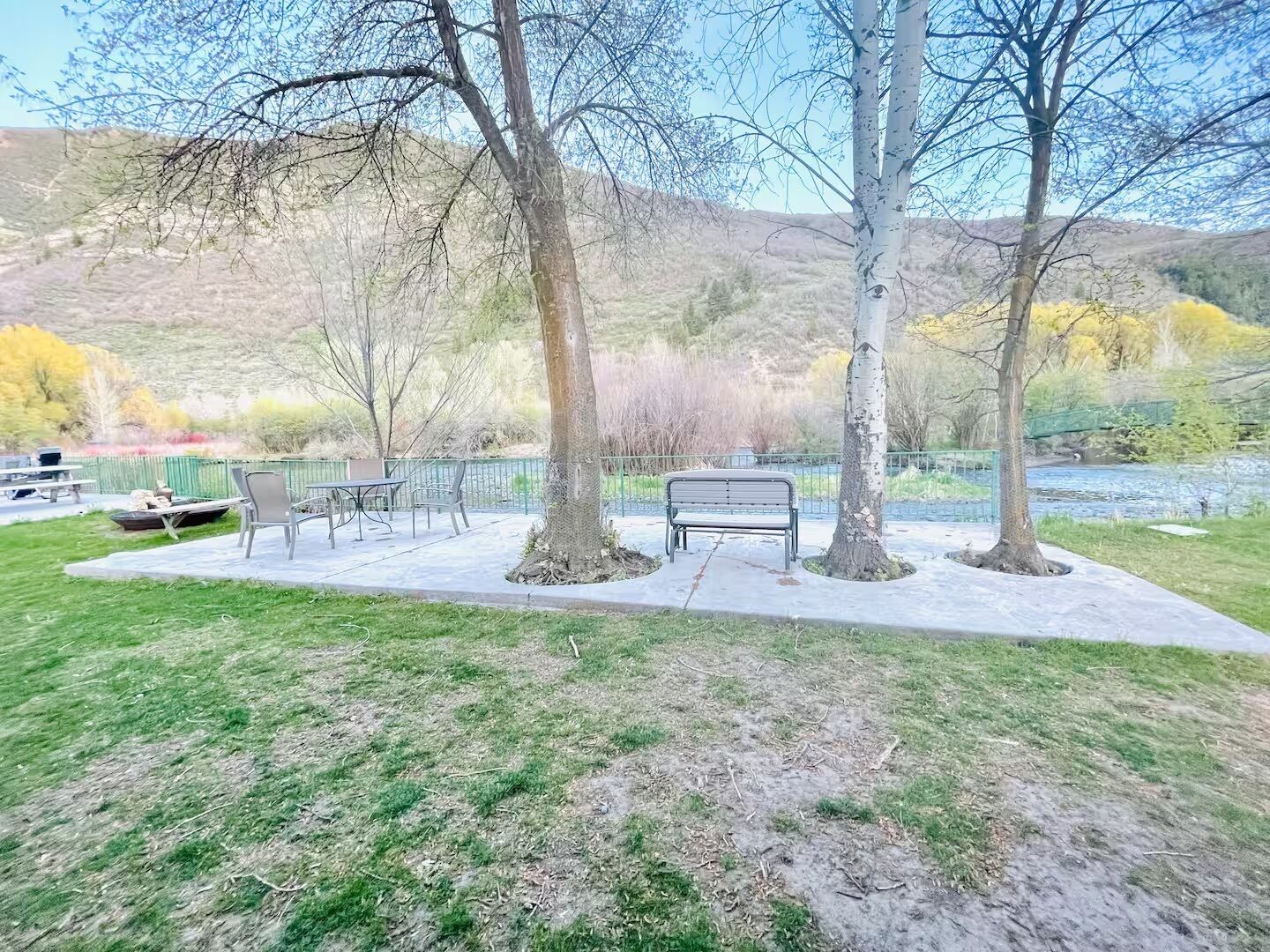 A park with a bench, picnic tables, and a river.