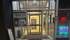 L’entrée d’un hôtel, avec une porte en verre, une enseigne indiquant le numéro 1039 et un ascenseur bien visible.