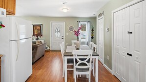 A kitchen with a dining table, chairs, a refrigerator, a clock, and a door. - Cozy 2-bedroom house in perfect Westerly with AC. Big,  open back yard! (Westerly)