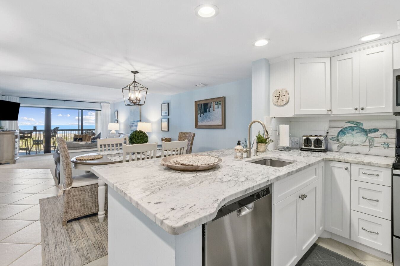 A modern kitchen with white cabinetry, a marble countertop, and a built-in dishwasher.