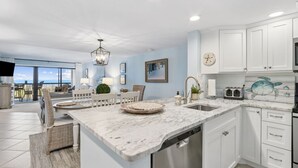 Una cocina moderna con armarios blancos, encimera de mármol y lavavajillas integrado.