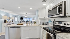 Una cocina moderna con armarios blancos, horno empotrado, microondas y una isla grande con lavamanos.