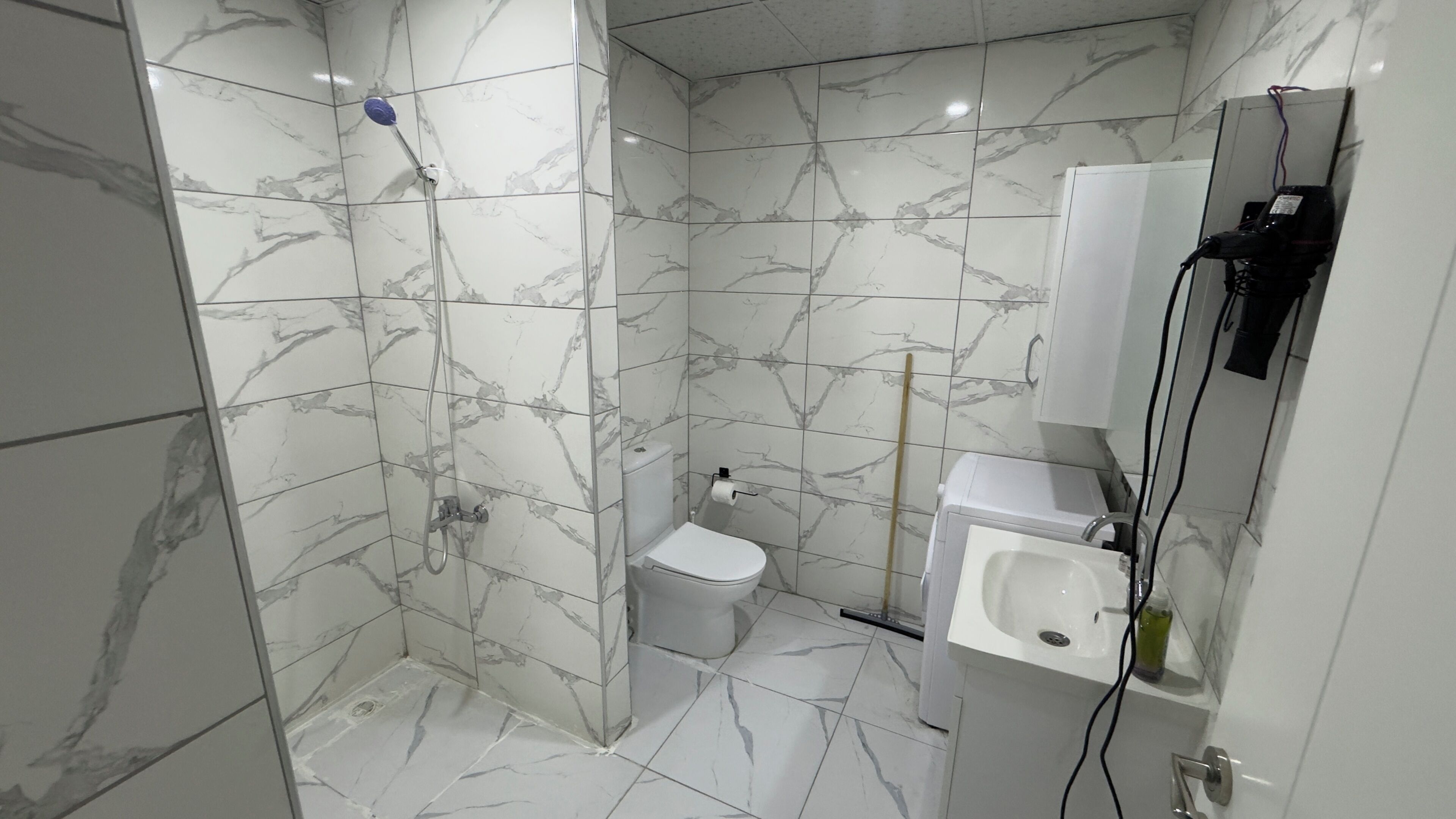 A bathroom with a shower, toilet, sink, and a mirror.