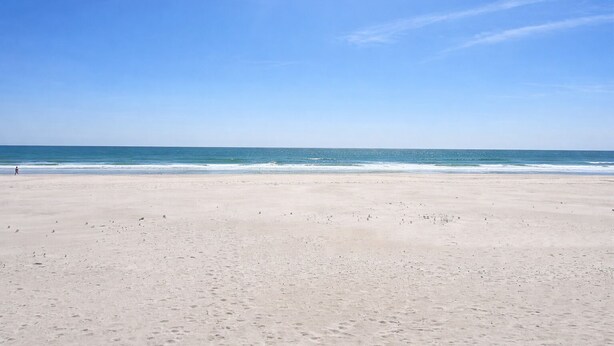 A wide sandy beach with a clear blue sky and calm ocean. - Show Me Carolina, Steps to Beach, Pet Friendl (Topsail Beach)