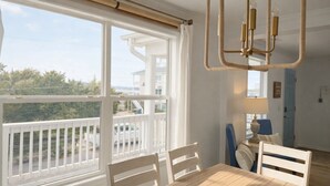 A room with a large window, a dining table with chairs, a hanging light fixture, and a view of the outside. - Show Me Carolina, Steps to Beach, Pet Friendl (Topsail Beach)
