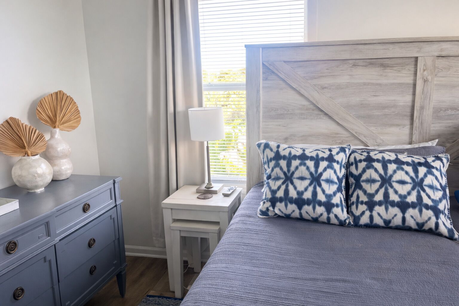 Une chambre à coucher comprenant un lit, une table de chevet avec une lampe, une commode et des vases décoratifs.