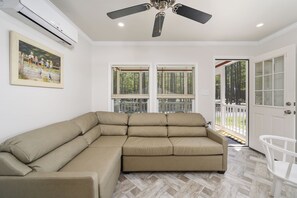 A living room with a sectional sofa, a ceiling fan, and a painting on the wall.