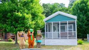 A small building with a porch, surrounded by trees. - Jellystone Park Delaware Beaches (Lincoln)