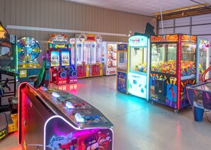 An indoor arcade with various gaming machines, including a spinning wheel game and claw machines.