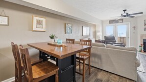 A dining area with a wooden table and chairs, a sofa, and a ceiling fan.