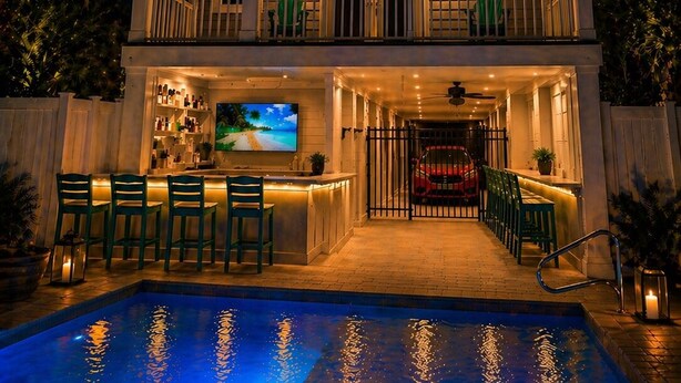 A two-story waterfront property with a bar area, outdoor seating, and a swimming pool.