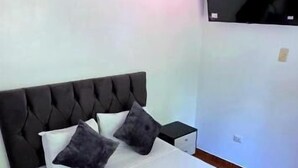 Een bed met een gestoffeerd hoofdbord, witte beddengoed en twee kussens. Een handdoek ligt op het bed.