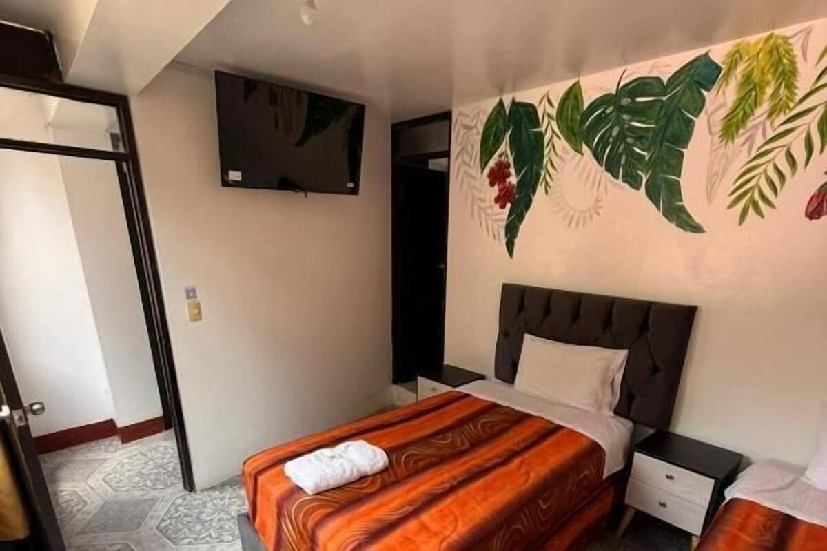 Una habitación de hotel con dos camas, un televisor montado en la pared y un suelo con diseño.