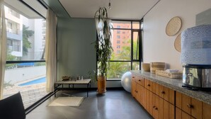 A modern kitchen with a large window, a potted plant, and a water dispenser. - Apto em Campo Belo 20min Aeroporto CGH (São Paulo)