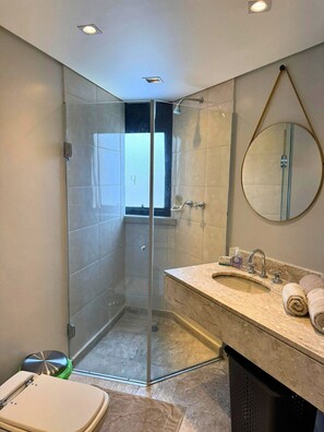 A bathroom with a glass-enclosed shower, a sink with a marble countertop, a mirror, and a toilet. - Apto em Campo Belo 20min Aeroporto CGH (São Paulo)