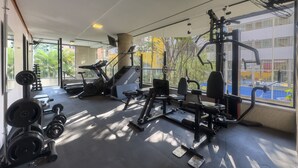 A gym with exercise equipment, a treadmill, and a weight rack. - Apto em Campo Belo 20min Aeroporto CGH (São Paulo)