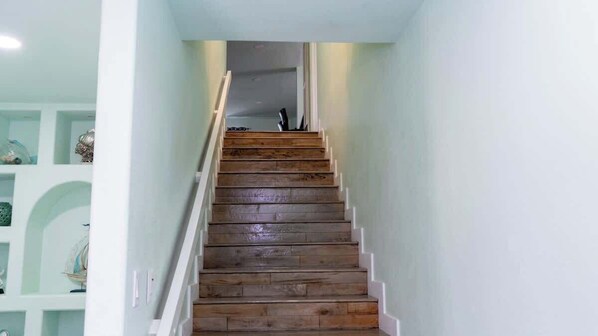 Un escalier en bois avec des rampes blanches menant à un palier.