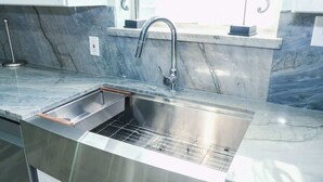 A modern kitchen with a stainless steel sink, a built-in oven, and a marble backsplash. - Channelfront - Remodeled - Pool - Boatslips (Port Isabel)