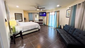 A hotel room with a bed, a sofa, a TV, and curtains. - Channelfront - Remodeled - Pool - Boatslips (Port Isabel)