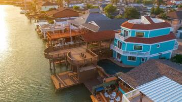 A waterfront property with a multi-level structure, outdoor seating, and a pool.