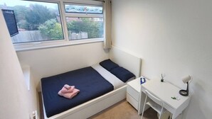 A small, single-bed room with a window, a desk, and a chair. - Room-cosy Small Double Room in Quiet Sha (Chelmsford)